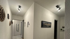 Ein Flur mit weißen Wänden, einem gerahmten Bild und einer Tür.