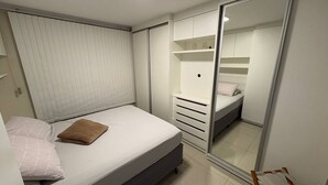 Un dormitorio con cama, armario y espejo.