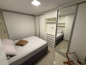 Um quarto com cama, guarda-roupa e espelho.