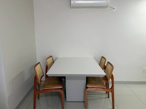 A dining area with a white table and four wooden chairs with woven backs.
