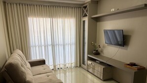 Una sala de estar moderna con un sofá, un televisor montado en la pared y un ventanal corredero.