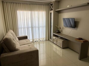 A modern living room with a sofa, a TV mounted on the wall, and a sliding glass door.