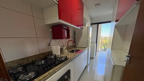 Una cocina con estufa a gas, horno y armarios rojos.