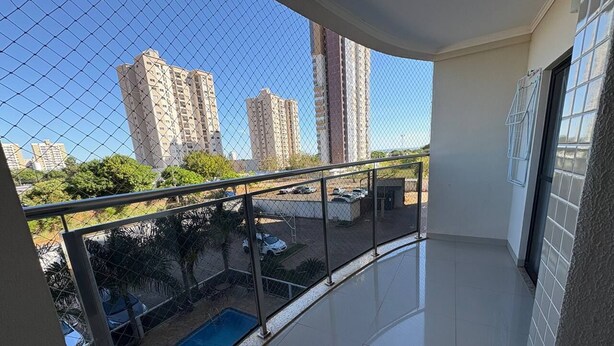 Un balcón con vistas a edificios altos, una piscina y un área cercada.