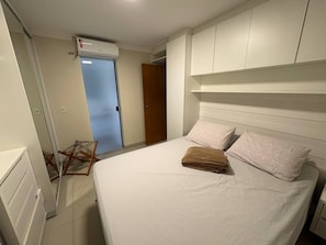 A bedroom with a bed, white bedding, a wooden door, and a ceiling fan.