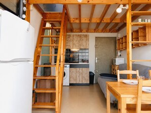 Eine kompakte Küche mit Holzausbau, einer Waschmaschine und einem Essbereich mit Tisch und Stühlen.
