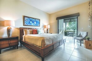 Ein Schlafzimmer mit Bett, Nachttischen, einem Sessel und Blick ins Freie.
