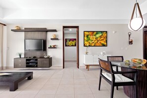 Ein modernes Wohnzimmer mit Fernseher, Unterhaltungseinheit, Esstisch, Stühlen und Kunstwerken.
