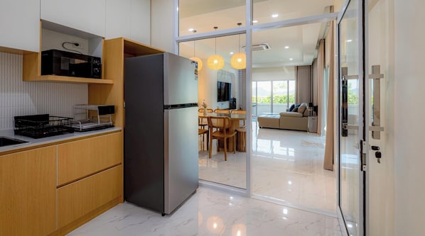 Eine moderne Küche mit Kühlschrank, Holzschränken und einem Essbereich mit Tisch und Stühlen.