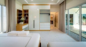 Ein modernes Hotelzimmer mit einem großen Bett, einem Einbauschrank, einer Sitzecke und einem Balkon mit Blick auf den Pool.
