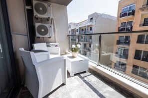 Ein Balkon mit weißer Möbel, Klimaanlagen und einem Blumentopf.