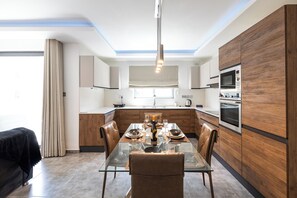 Eine moderne Küche mit einem Glastisch, Holzschränken und einem eingebauten Backofen.