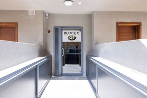 Ein Korridor mit einer Tür, auf der 'BLOCK C' steht, und einem Rauchmelder an der Wand.