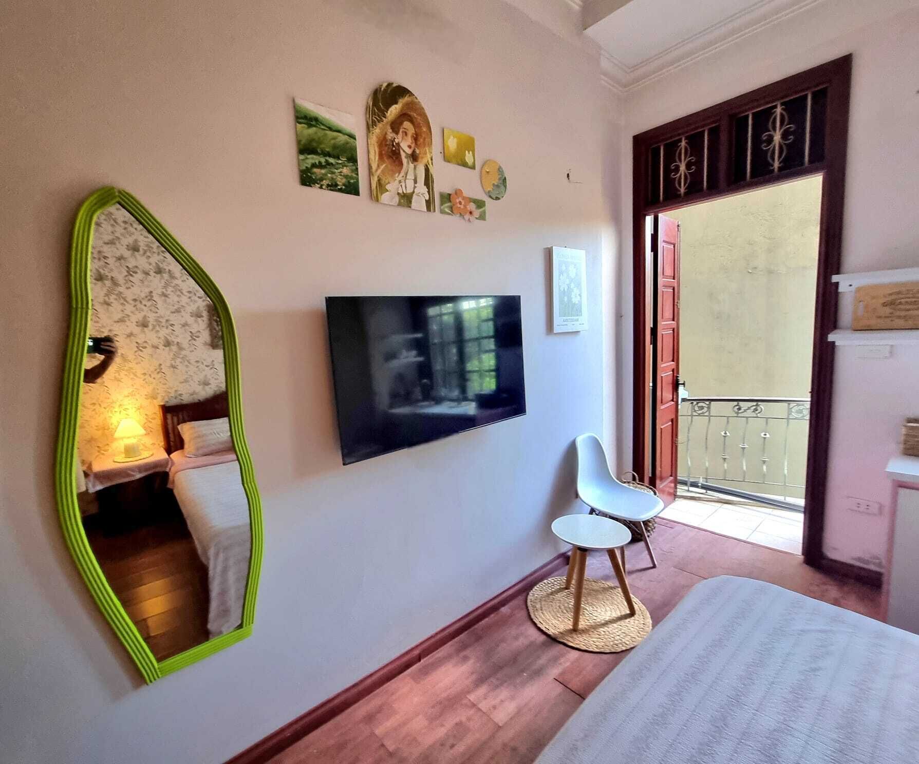 A bedroom with a bed, a TV, a chair, and a mirror.