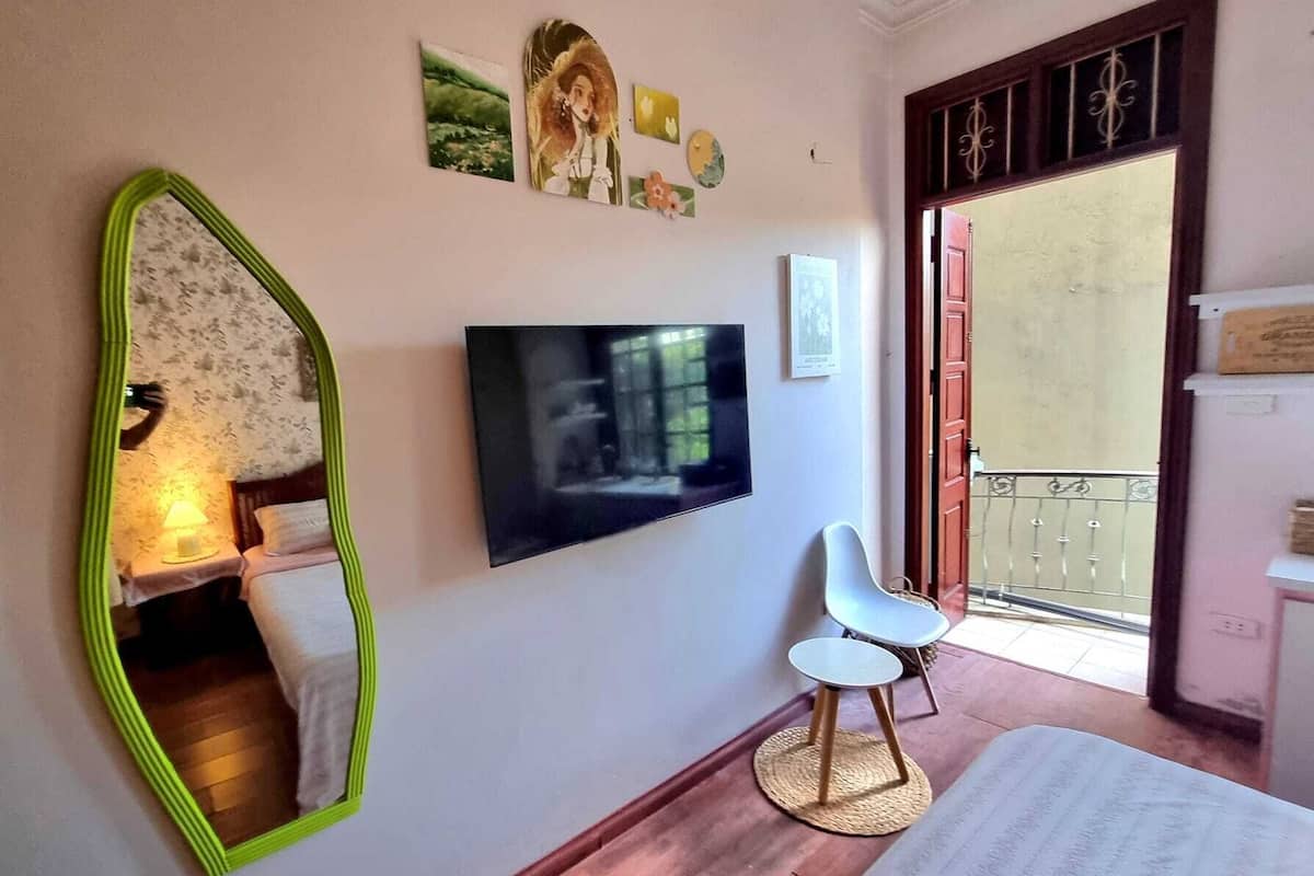 A bedroom with a bed, a TV, a chair, and a mirror.