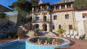 Un edifici de pedra gran amb piscina, un balcó i una escala que condueix a l'entrada.