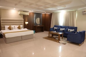 Quarto de hotel com uma cama, um sofá, uma mesa de centro e um espelho.