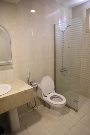 A bathroom with a toilet, sink, and glass shower enclosure. - Durrat Al Masaken Serviced Apartment (Al Khobar)