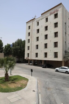 Un edificio de varios pisos con fachada plana, varias ventanas y un letrero que indica que es un hotel.