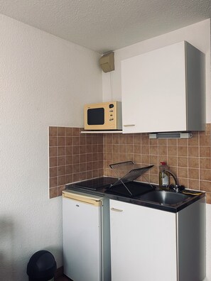 Une cuisine compacte équipée d’un four à micro-ondes, d’un évier et d’un petit réfrigérateur.