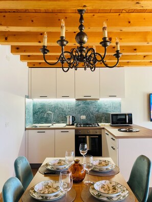 Een moderne keuken met een houten plafond, een kroonluchter, een magnetron en een eethoek gedekt met borden en glazen.