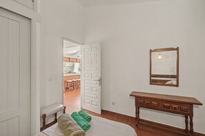 A room with a bed, a wooden bench, a mirror, and a door leading to a kitchen. - Holiday Apartment 'Los Porches K28' with Shared Pool, Private Terrace & Wi-Fi (Maspalomas)