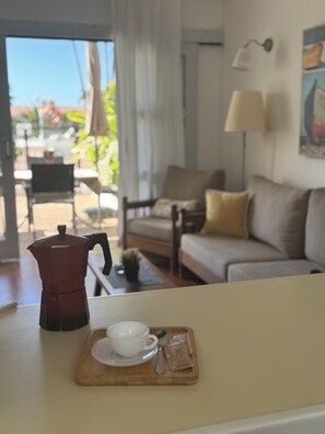 Ein Zimmer mit einer Kaffeemaschine auf einem Tisch, einem Sofa, einem Sessel und einer Lampe.
