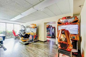 Ein Indoor-Arcade mit verschiedenen Spielautomaten, einem roten Sessel und einem Fenster, das natürliches Licht hereinlässt.