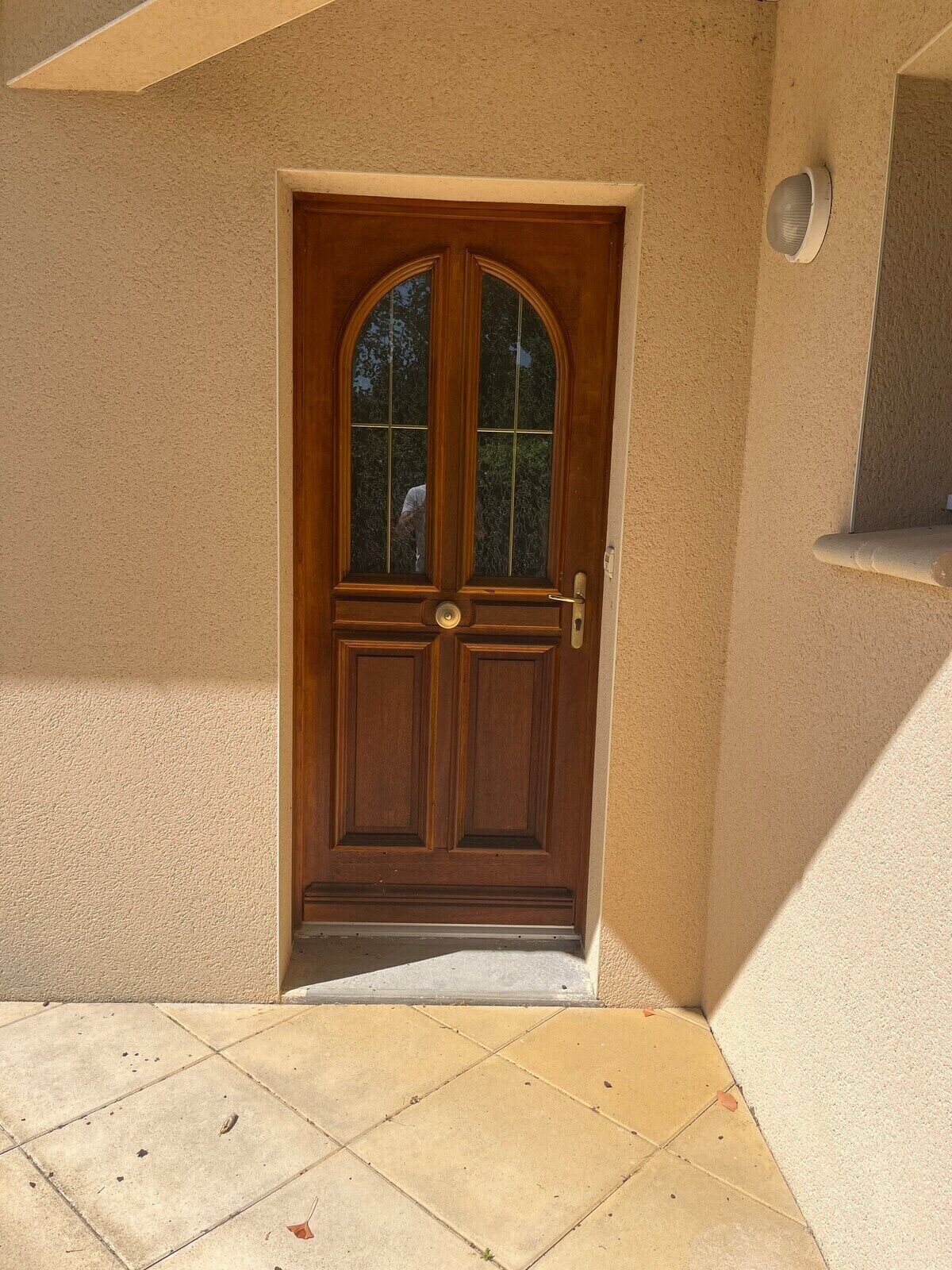A wooden door with a glass panel, a metal handle, and a keyhole.
