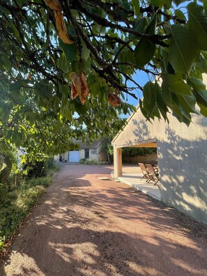 A gravel path leading to a building with a covered patio area. - Gîte Le Clocher du Layon (Nueil Sur Layon)