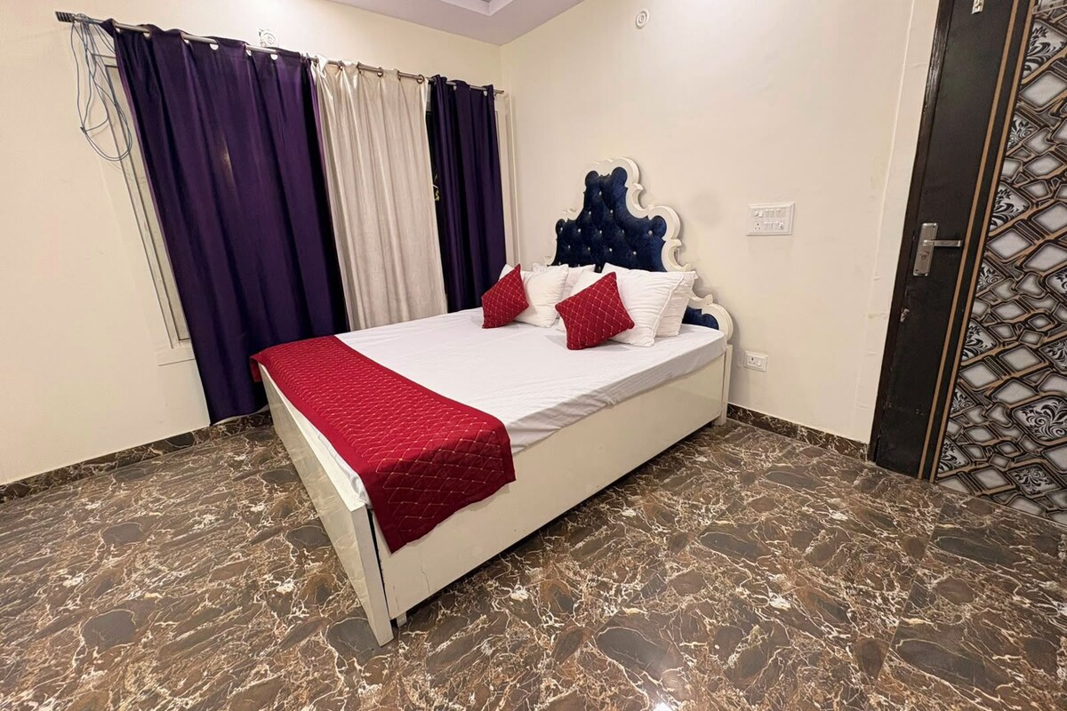 Una camera da letto con un letto, tende, una testiera e una porta con motivo decorativo.