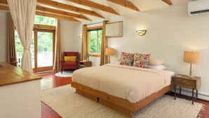 Un dormitorio con una cama de madera, una silla roja, una mesita de noche pequeña y una ventana con cortinas.