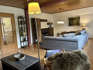 Ein Wohnzimmer mit Sofa, Fernseher, Lampe und einem Bild an der Wand.