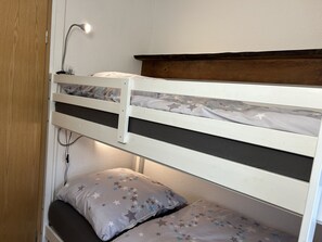 Ein Stockbett mit Kopfteil, einer Nachttischlampe und einem Kissen mit Sternenmuster.