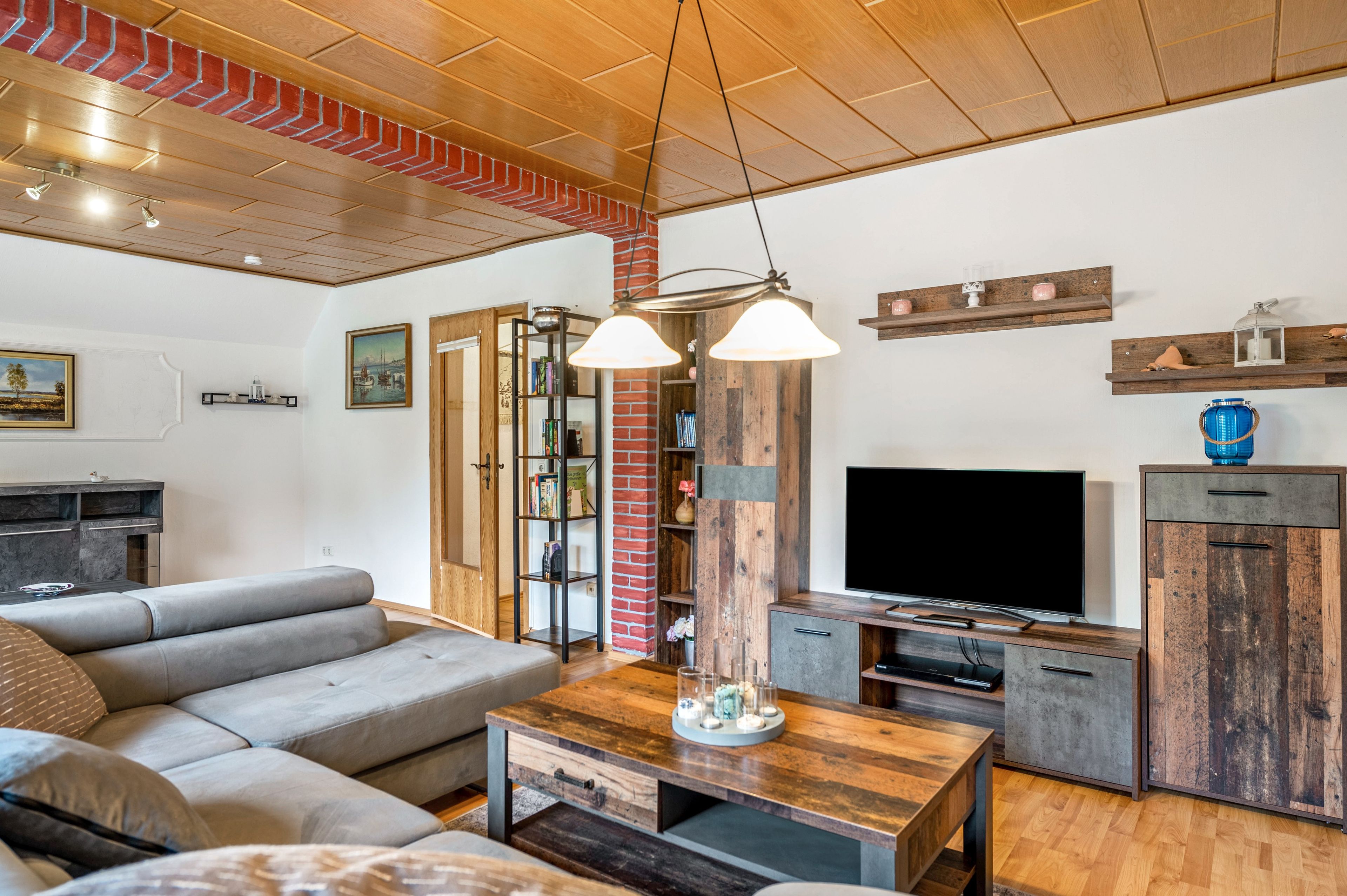 Ein modernes Wohnzimmer mit einer Couch, einem Couchtisch, einem Fernseher und Holzelementen.