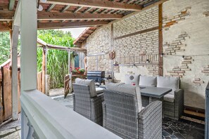 Eine Terrasse im Freien mit Korbmöbeln, einer Ziegelwand und einem Grill.