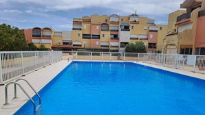 A swimming pool with a white fence, surrounded by multi-story buildings. - Well-located, quiet studio with a pool (Gruissan)