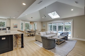 A spacious living area with a dining table, sofas, and a large window with a view. - 3 Jessamine - A Coastal Comfort Escape Available Starting August 2026! (Hilton Head Island)