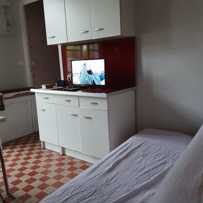 Ein Zimmer mit einem Bett, einem Fernseher auf einer Kommode und einem Schachbrettmuster-Boden.