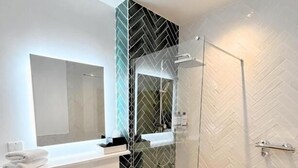 A modern bathroom with a glass shower enclosure, a white sink, and a mirror.