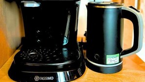 Una cafetera y una taza sobre un estante de madera.