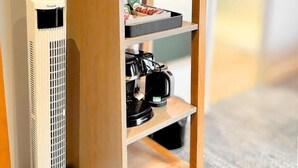 Una estantería de madera con una cafetera, dos tazas y una bandeja pequeña con alimentos.