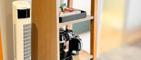 A wooden shelf with a coffee maker, two cups, and a small tray with food items.