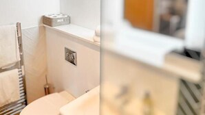 Un baño pequeño con inodoro, lavamanos y un perchero para toallas.