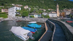 Ein Hafen mit Booten, einer Steinmauer und Gebäuden mit einem Glockenturm.