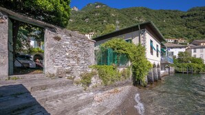 Ein Steinhaus mit Balkon, einem Fluss und einem Berg im Hintergrund.