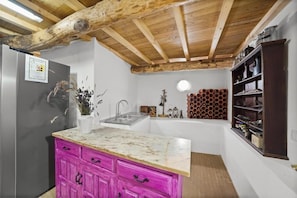 Una cocina con techo de madera, un lavamanos, un refrigerador y un armario rosa.