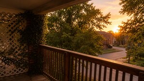 A wooden deck with a lattice fence, overlooking a residential street during sunset. - Modern 2BD 1BA Near OSU Fairgrounds FREE Parking (Columbus)