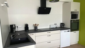 A modern kitchen with a black countertop, white cabinetry, a built-in microwave, and an oven.