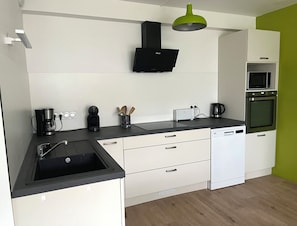 Eine moderne Küche mit schwarzer Arbeitsplatte, weißen Schränken, einer eingebauten Mikrowelle und einem Backofen.
